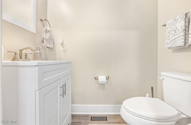 bathroom with toilet, vanity, and hardwood / wood-style flooring