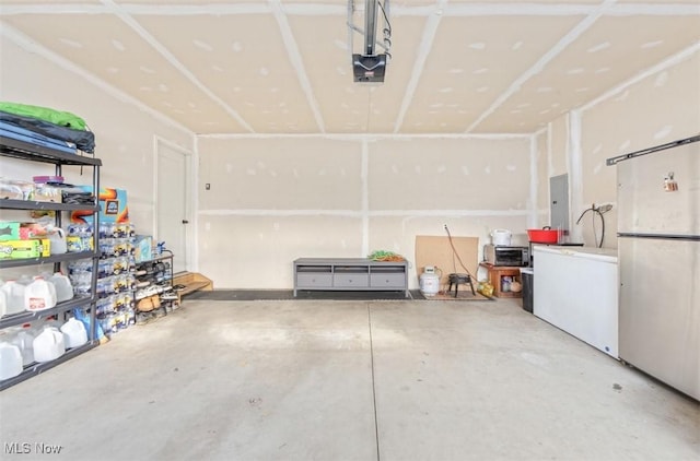 garage featuring refrigerator, electric panel, and a garage door opener