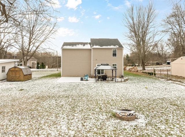 rear view of property featuring a gazebo, a storage shed, and an outdoor fire pit