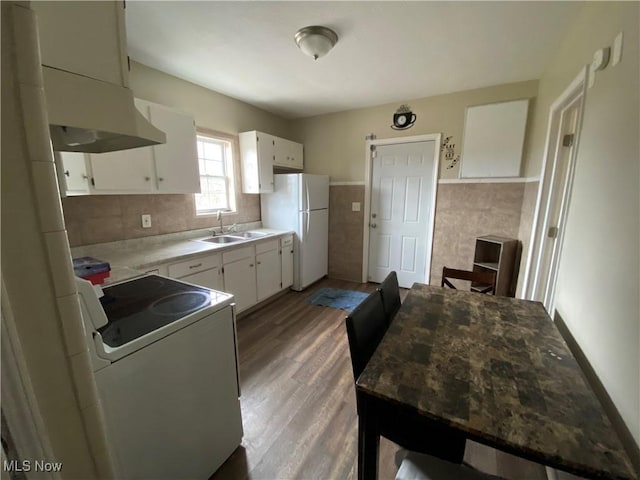 kitchen with white cabinetry, sink, extractor fan, white appliances, and hardwood / wood-style flooring