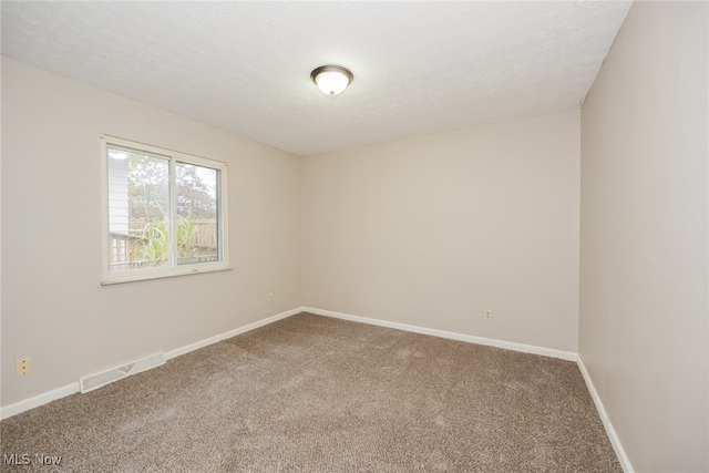 carpeted empty room featuring a textured ceiling