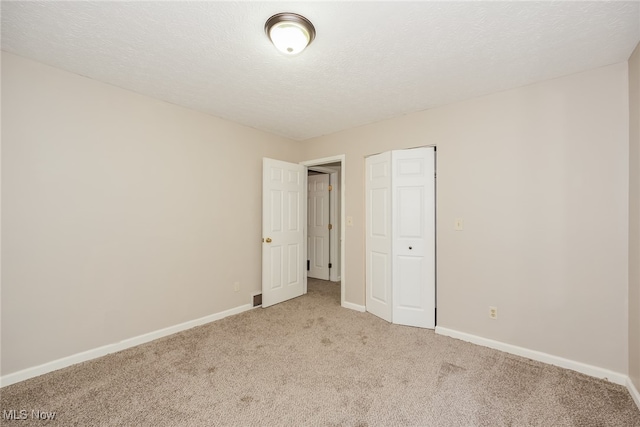 unfurnished bedroom with light carpet, a textured ceiling, and a closet