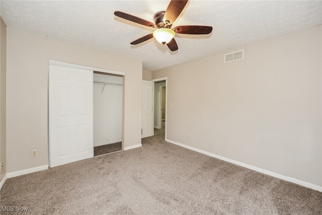 unfurnished bedroom with ceiling fan, carpet floors, a textured ceiling, and a closet