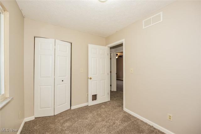 unfurnished bedroom with light carpet, a closet, and a textured ceiling