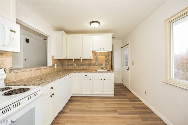 kitchen with light wood-type flooring, white appliances, tasteful backsplash, and white cabinetry