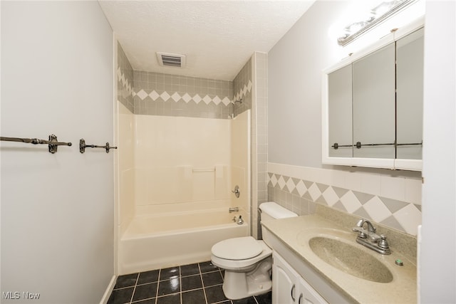 full bathroom with tile patterned flooring, a textured ceiling, toilet, vanity, and tiled shower / bath