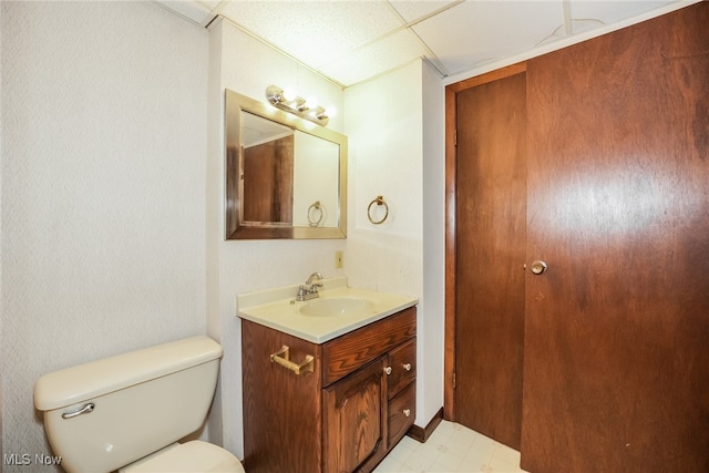 bathroom featuring vanity, toilet, and a drop ceiling