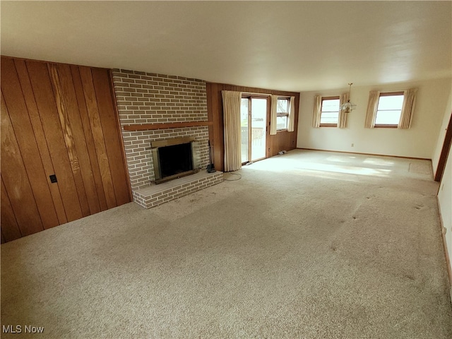 unfurnished living room with carpet, wood walls, and a fireplace