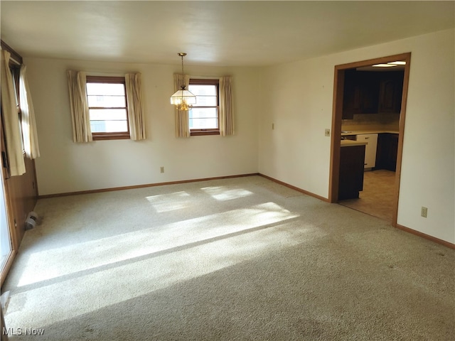 unfurnished room with a notable chandelier, light carpet, and a wealth of natural light