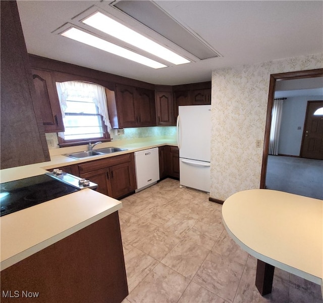 kitchen with dark brown cabinets, sink, and white appliances