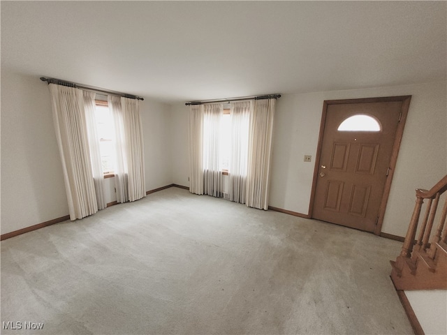 foyer entrance with light carpet and a healthy amount of sunlight