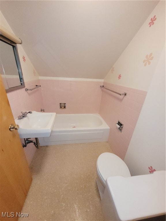 bathroom featuring sink, vaulted ceiling, toilet, tile walls, and a tub