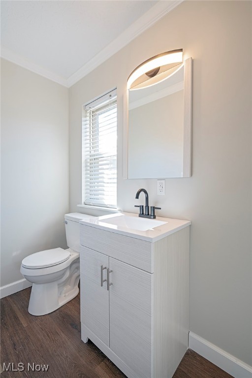 bathroom with toilet, hardwood / wood-style floors, vanity, and ornamental molding