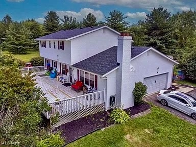 rear view of house with covered porch, a yard, a garage, and a wooden deck