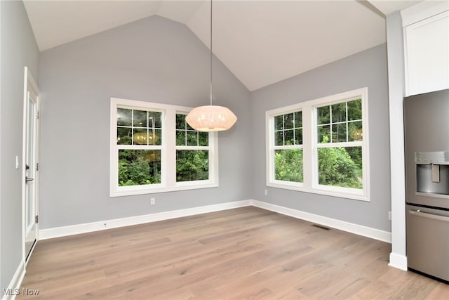 unfurnished dining area featuring light wood-type flooring and high vaulted ceiling