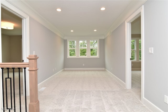 unfurnished room featuring a wealth of natural light, crown molding, and light carpet