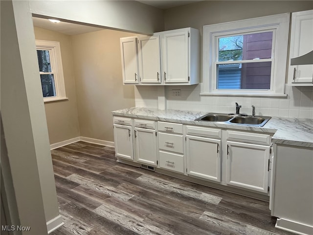 kitchen featuring decorative backsplash, light stone countertops, sink, white cabinets, and dark hardwood / wood-style floors