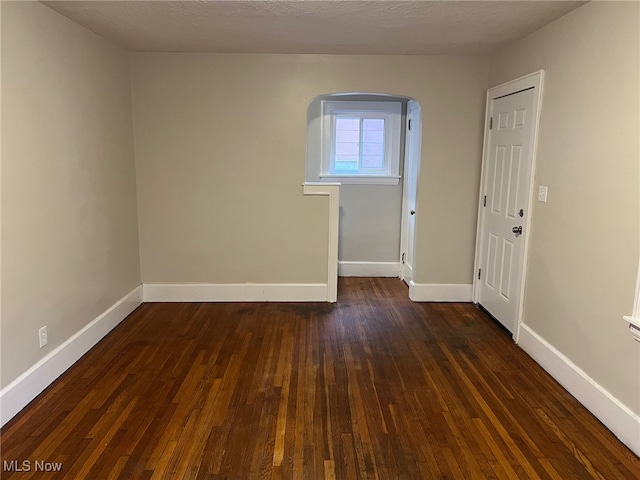 unfurnished room featuring dark hardwood / wood-style flooring and a textured ceiling