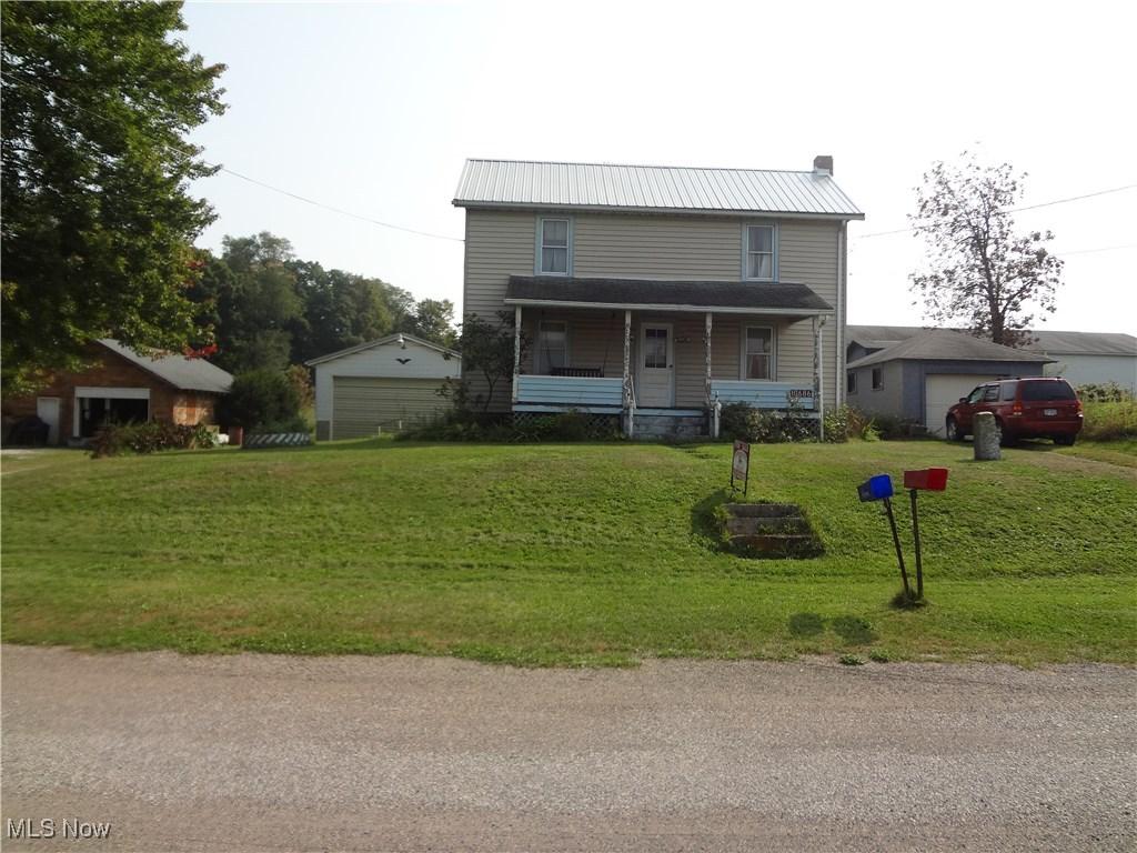 10686 Common St, East Rochester, OH 44625 - view of front of home with a detached garage, covered porch, a front yard, and metal roof