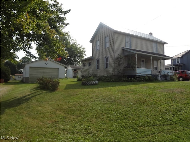 exterior space featuring a lawn, a garage, an outbuilding, and covered porch