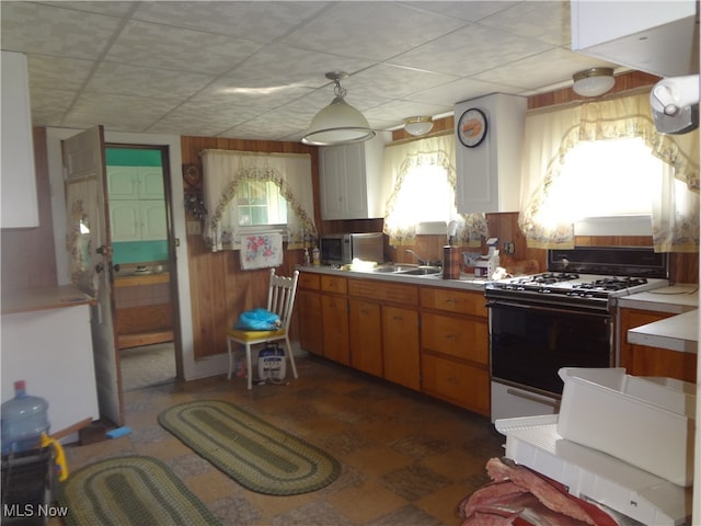 kitchen featuring white range with gas stovetop and wooden walls