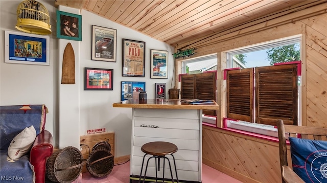 interior space with wooden walls, lofted ceiling, wood ceiling, and bar area