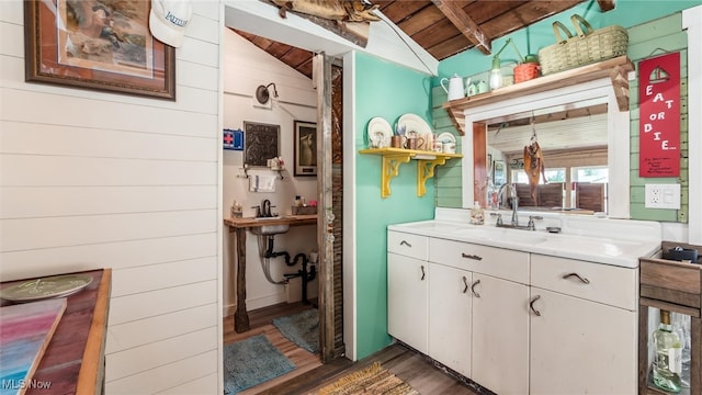 bathroom featuring wood walls, lofted ceiling with beams, sink, hardwood / wood-style flooring, and wood ceiling