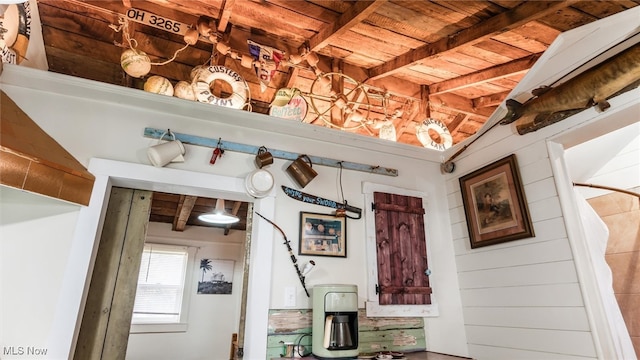 interior space featuring beam ceiling, wooden walls, and wood ceiling