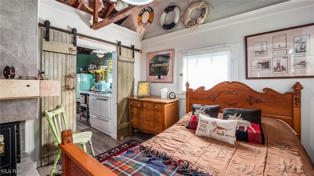 bedroom with a barn door and hardwood / wood-style flooring