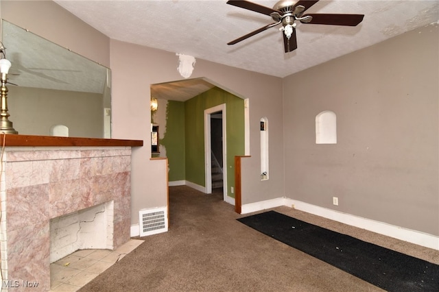 unfurnished living room featuring light carpet, a textured ceiling, and ceiling fan