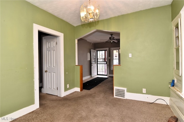 carpeted foyer entrance with a textured ceiling and ceiling fan with notable chandelier