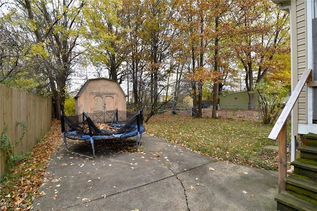 view of yard with a trampoline, a shed, and a patio area