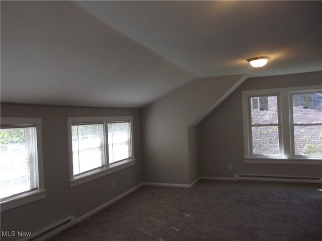 additional living space with dark carpet, lofted ceiling, and a baseboard heating unit