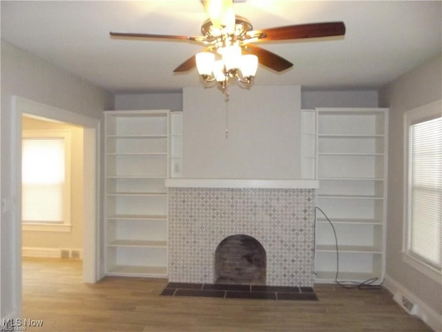 unfurnished living room with hardwood / wood-style floors, ceiling fan, and a tiled fireplace