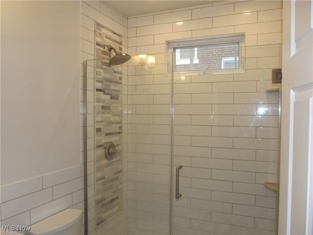 bathroom featuring toilet, tile walls, and walk in shower