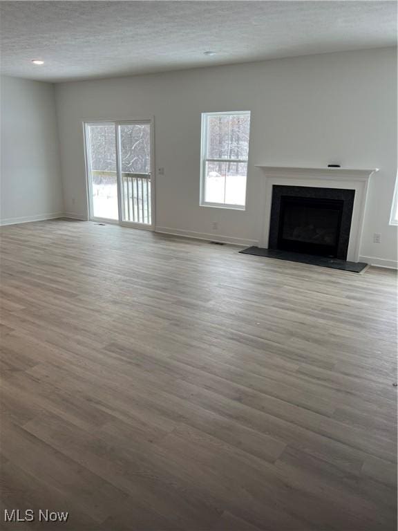 unfurnished living room with a textured ceiling and light hardwood / wood-style flooring