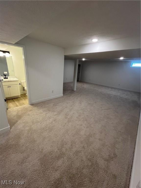 basement featuring sink and light carpet