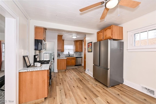 kitchen featuring tasteful backsplash, a healthy amount of sunlight, appliances with stainless steel finishes, and light hardwood / wood-style flooring