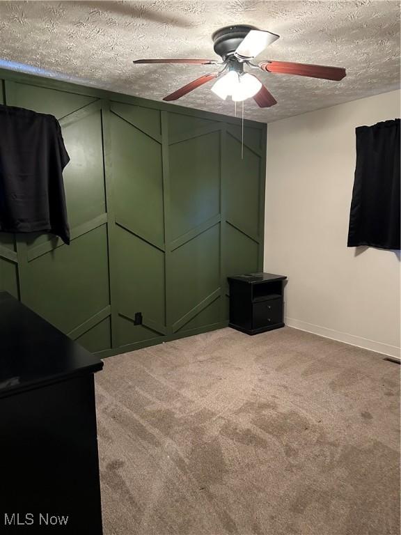 unfurnished bedroom featuring ceiling fan, light carpet, and a textured ceiling