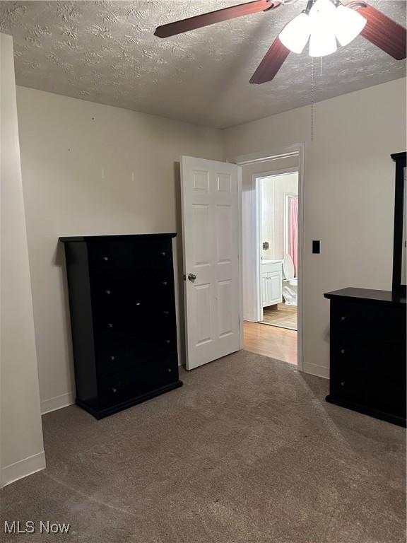 unfurnished bedroom featuring carpet, a textured ceiling, ceiling fan, and connected bathroom