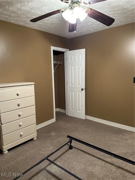 unfurnished bedroom with ceiling fan, a closet, carpet, and a textured ceiling