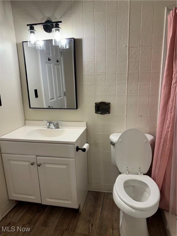 bathroom with hardwood / wood-style floors, vanity, toilet, and tile walls