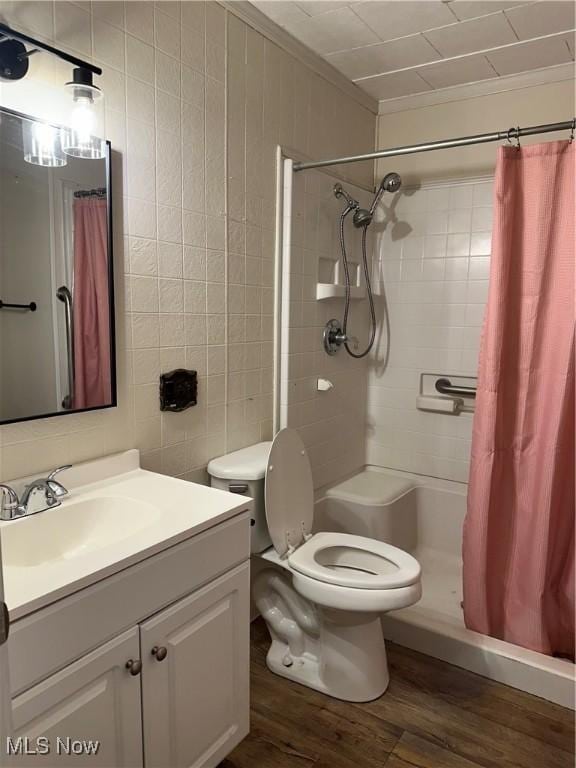 bathroom featuring wood-type flooring, curtained shower, ornamental molding, and tile walls