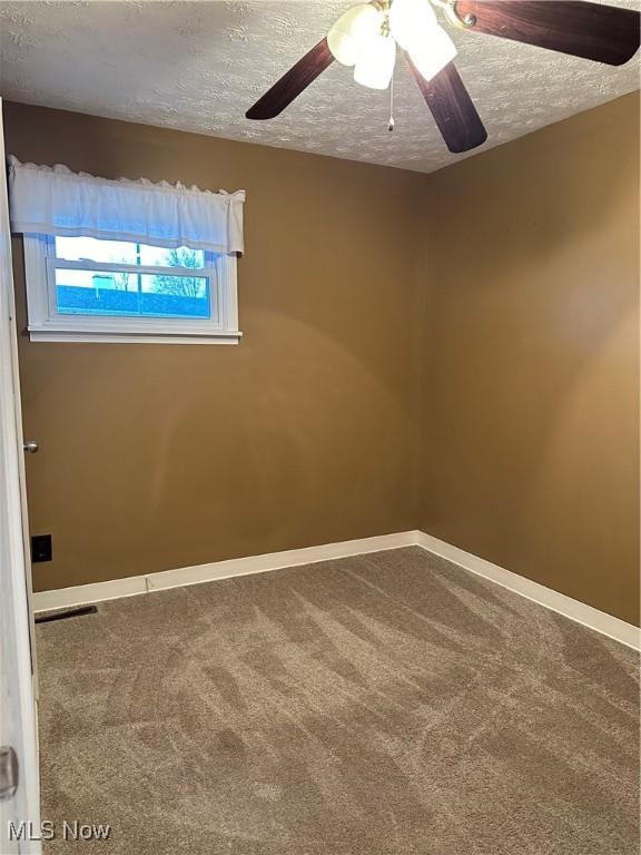 carpeted empty room featuring ceiling fan and a textured ceiling