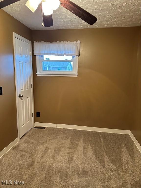 spare room with carpet flooring, ceiling fan, and a textured ceiling