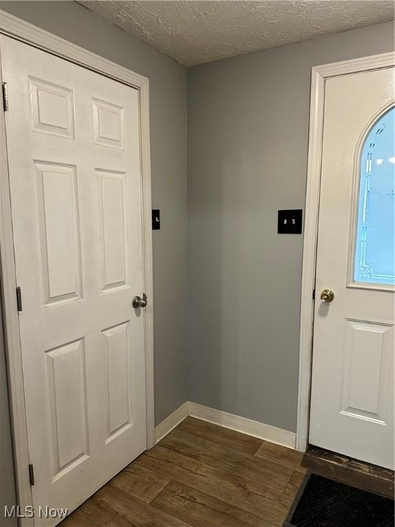 doorway to outside with a textured ceiling and dark wood-type flooring