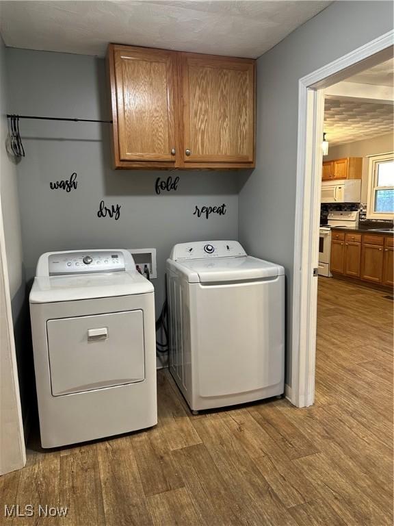 laundry area featuring cabinets, separate washer and dryer, and light wood-type flooring