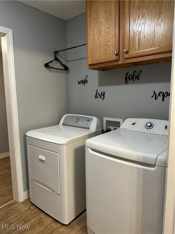 washroom featuring washer and dryer, cabinets, and wood-type flooring