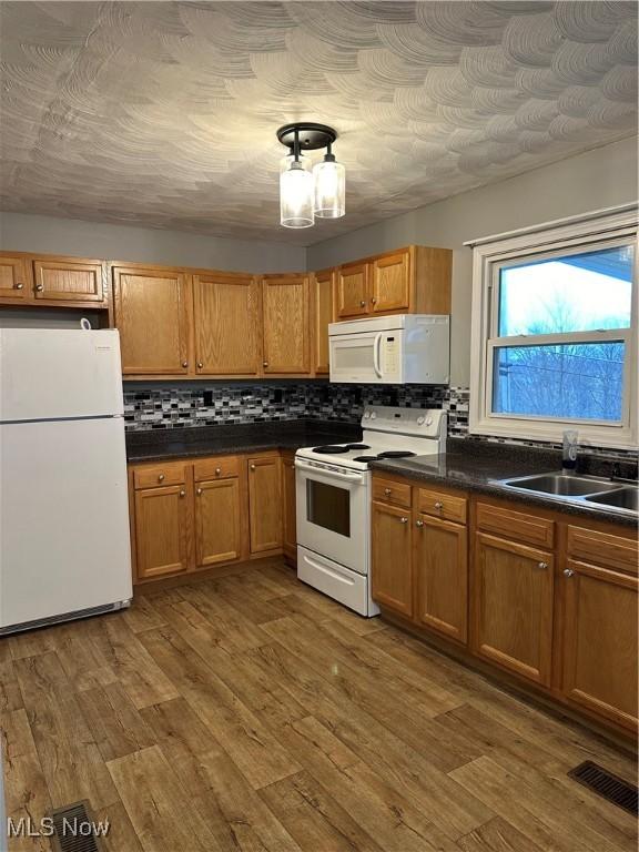 kitchen featuring backsplash, sink, dark wood-type flooring, and white appliances