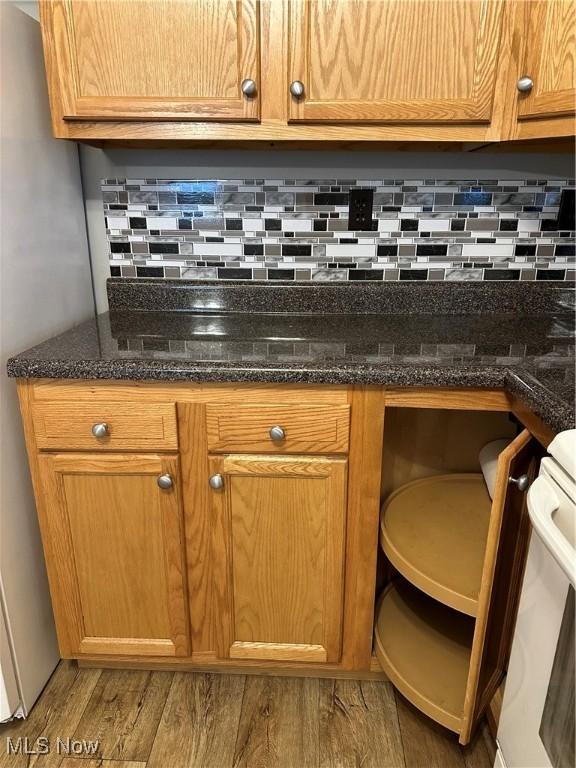 interior details featuring backsplash, stainless steel fridge, hardwood / wood-style floors, and stove